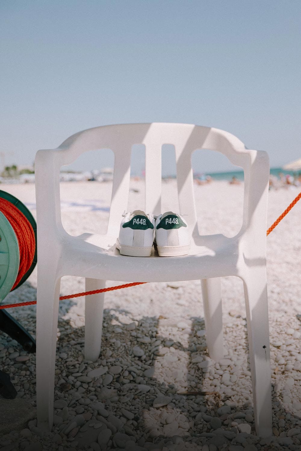 P448 white Sneakers with green heel tab on a seaside beach chair, summer Shoes
